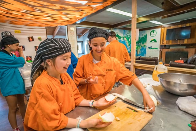 Kids in chef uniforms enjoying cooking class at summer camp kitchen. Kids in chef uniforms enjoying cooking class at summer camp kitchen.