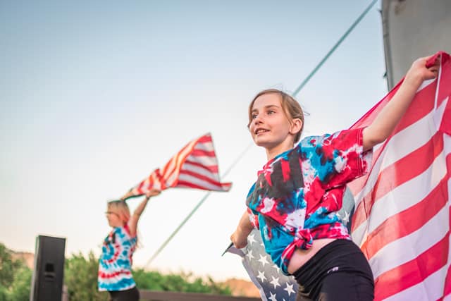 Kids celebrating with flags in tie-dye at summer camp. Happy outdoor activities for children. Perfect for summer camp fun.