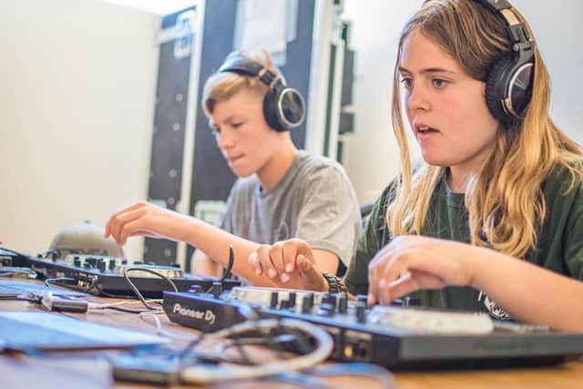 Kids learning DJ skills at summer camp, wearing headphones, focused on mixing music with equipment. Kids learning DJ skills at summer camp, wearing headphones, focused on mixing music with equipment.