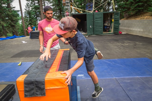 Child practicing parkour at summer camp while instructor supervises. Outdoor adventure and learning activities for kids. Child practicing parkour at summer camp while instructor supervises. Outdoor adventure and learning activities for kids.