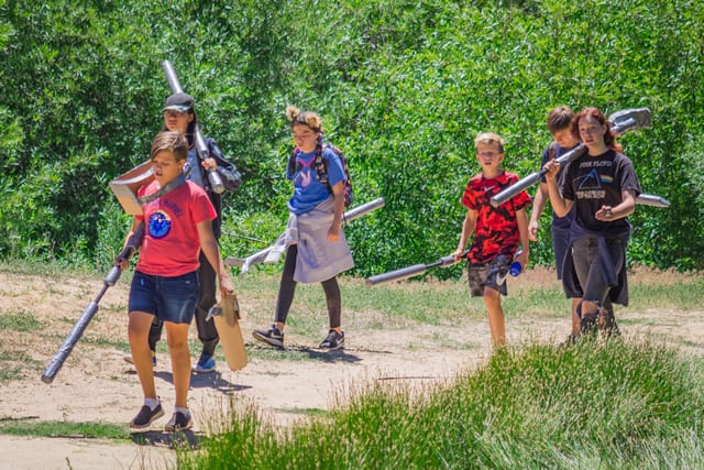Kids enjoying outdoor activities with foam swords at a summer camp, walking on a sunny trail. Kids enjoying outdoor activities with foam swords at a summer camp, walking on a sunny trail.