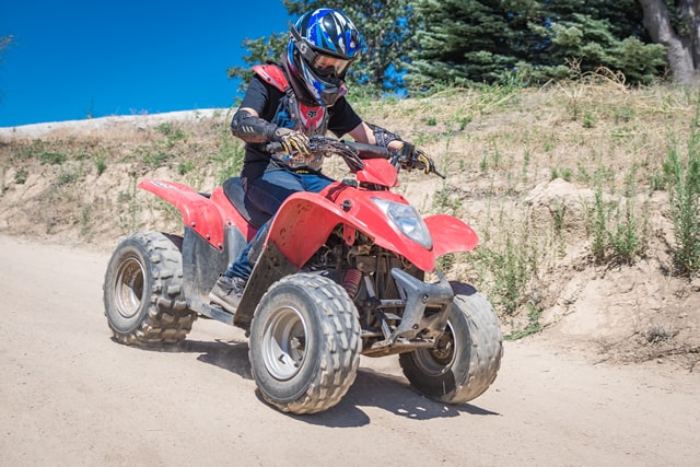 Child riding an ATV at a summer camp, outdoor adventure activity. Child riding an ATV at a summer camp, outdoor adventure activity.
