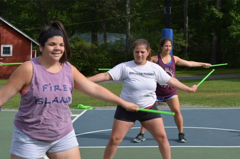 Women enjoying drumsticks dance activity at summer camp on a sunny day, surrounded by nature. Women enjoying drumsticks dance activity at summer camp on a sunny day, surrounded by nature.