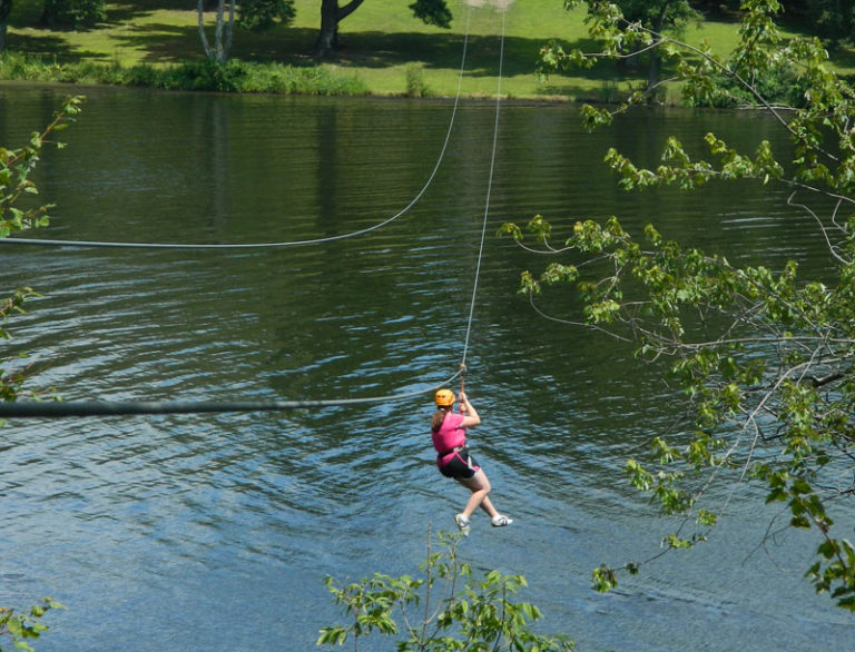 Child ziplining over lake at summer camp, enjoying outdoor adventure activity for fun and excitement. Child ziplining over lake at summer camp, enjoying outdoor adventure activity for fun and excitement.