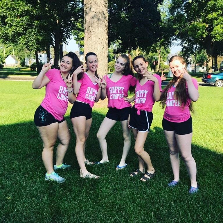 Group of campers in pink Happy Camper shirts posing joyfully on a sunny summer day at camp. Group of campers in pink Happy Camper shirts posing joyfully on a sunny summer day at camp.