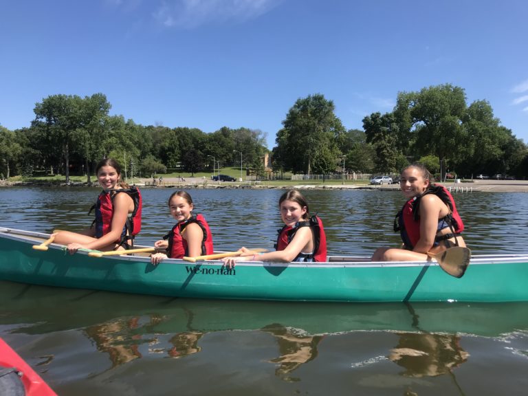 Kids canoeing at summer camp, enjoying outdoor activities on the lake under a clear blue sky. Kids canoeing at summer camp, enjoying outdoor activities on the lake under a clear blue sky.