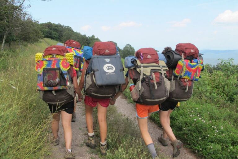 Campers hiking on trail with backpacks, enjoying a summer adventure through scenic nature. Campers hiking on trail with backpacks, enjoying a summer adventure through scenic nature.