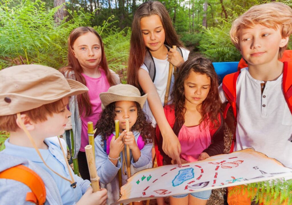 Children exploring nature with a map at summer camp, engaged in a fun outdoor treasure hunt activity.