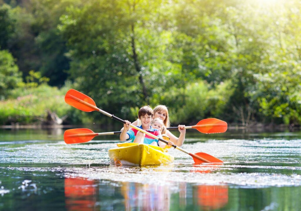 Family kayaking adventure at summer camp, enjoying nature and outdoor fun on a sunny day.