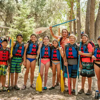 Campers enjoying canoeing at summer camp, wearing life vests and holding paddles in the forest. Campers enjoying canoeing at summer camp, wearing life vests and holding paddles in the forest.