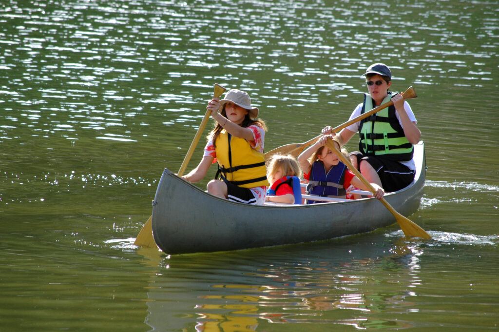 Family canoeing on a lake at summer camp, enjoying outdoor adventure and bonding.