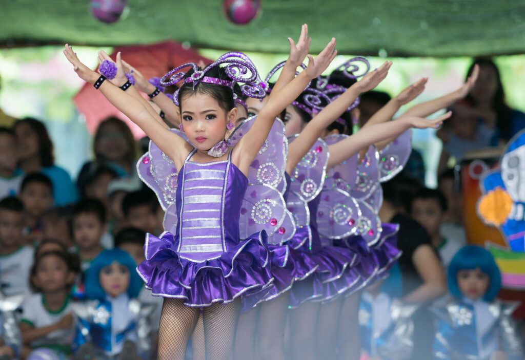 Children in butterfly costumes perform at a summer camp talent show, showcasing dance skills and creativity.