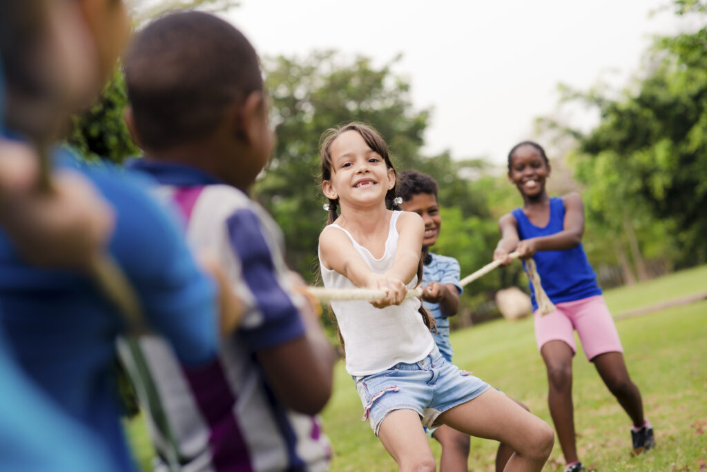 Children enjoying a tug-of-war game at summer camp, fostering teamwork and fun outdoors.