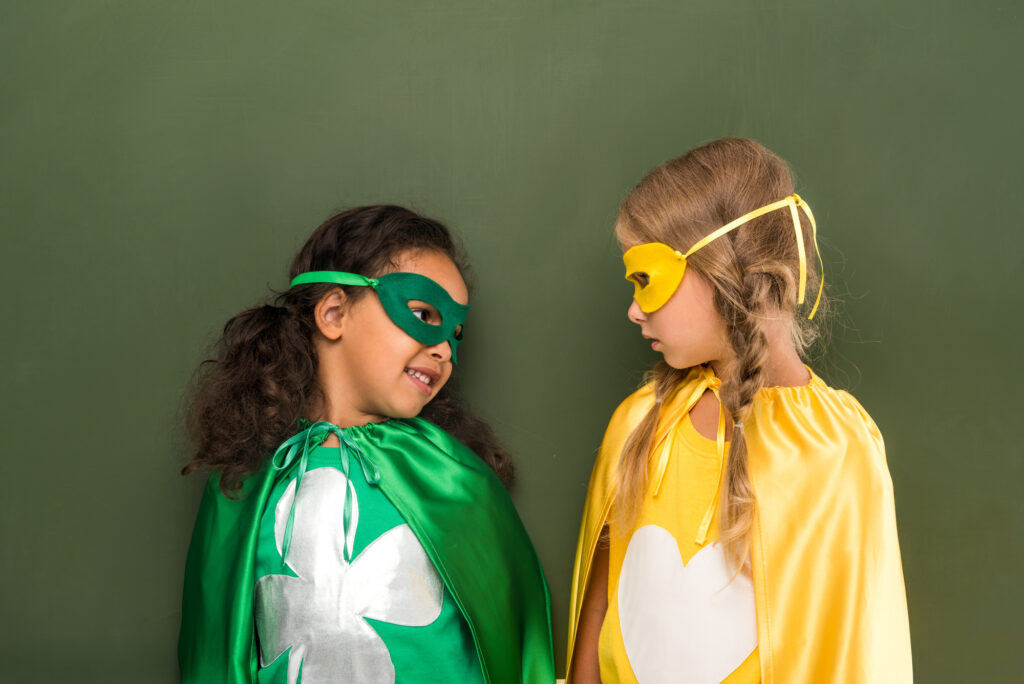 Two kids in superhero costumes at summer camp, wearing capes and masks, ready for adventure.