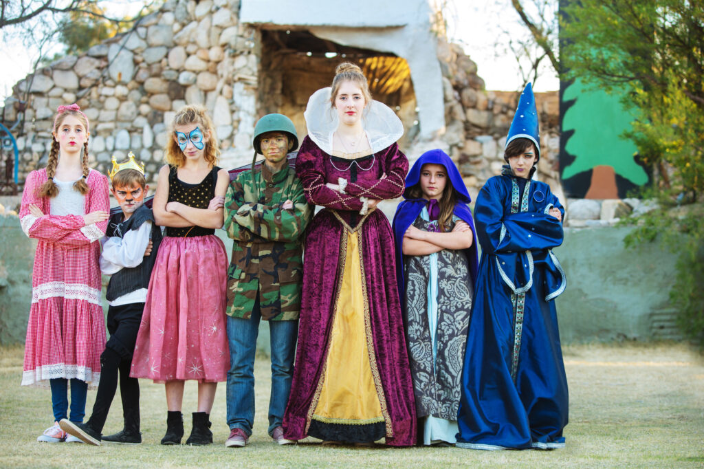 Children in colorful costumes pose outdoors, showcasing summer camp creativity and fun activities.