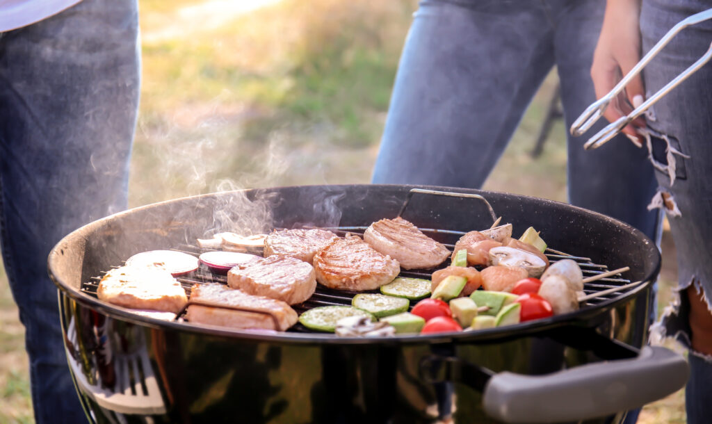 Grilling steaks and vegetables at summer camp cookout event. Perfect for youth outdoor adventures and meals.