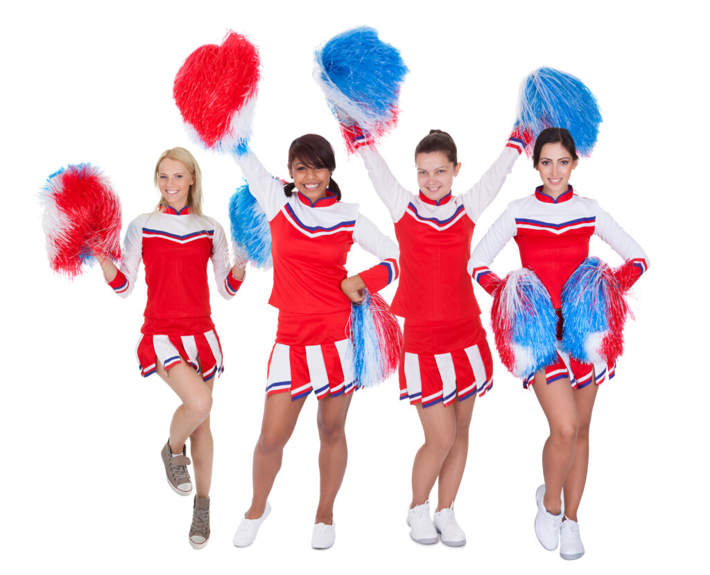 Cheerleaders in red uniforms with pom-poms at summer camp, showcasing team spirit and cheerleading fun.