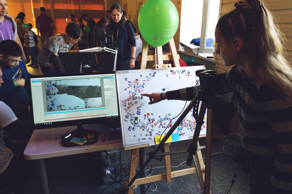 Kids engaging in a fun summer camp tech activity with computers and interactive displays.