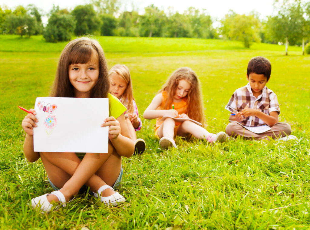 Children enjoying outdoor drawing activities at summer camp. Perfect for creativity and fun.