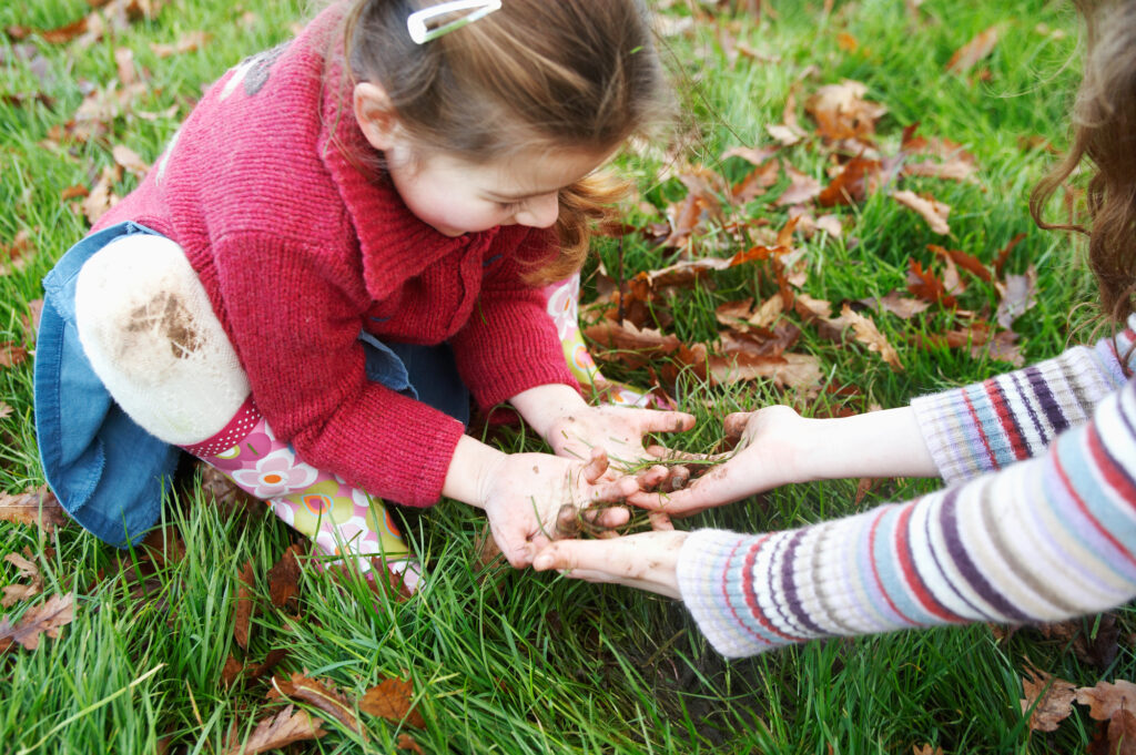 Children enjoying outdoor play with mud at a summer camp, enhancing creativity and connection with nature.