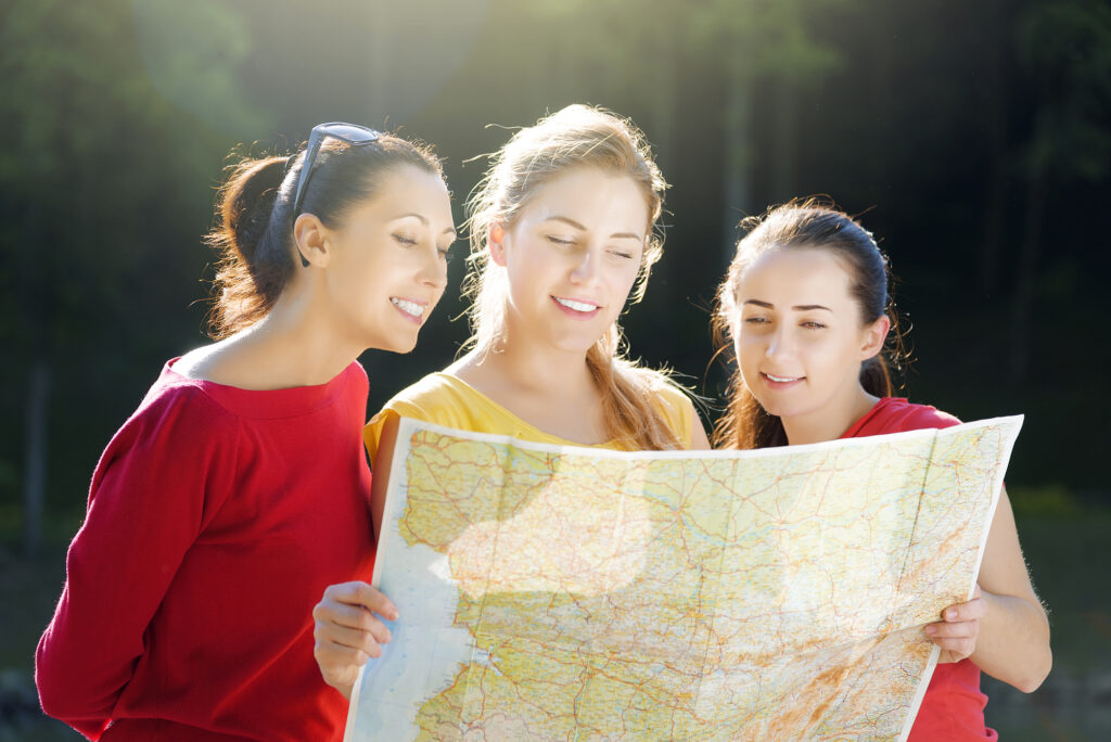 Young women exploring a summer campmap outdoors. Planning camp activities.