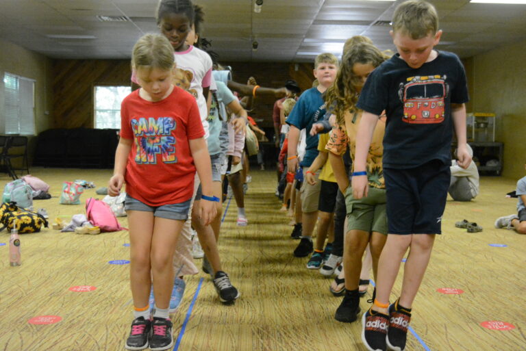 Children balancing on a line indoors at summer camp, engaging in a fun group activity. Children balancing on a line indoors at summer camp, engaging in a fun group activity.