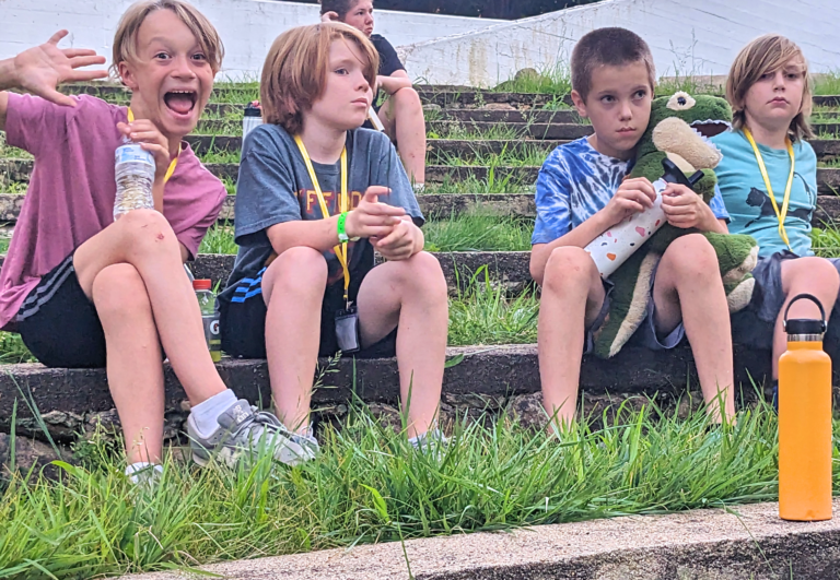 Kids enjoying outdoor activities at summer camp, sitting on grassy steps with toys and drinks. Kids enjoying outdoor activities at summer camp, sitting on grassy steps with toys and drinks.