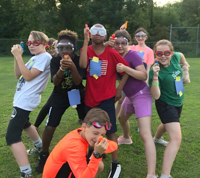 Kids enjoying water gun fun at summer camp, wearing goggles and playing on a grassy field. Kids enjoying water gun fun at summer camp, wearing goggles and playing on a grassy field.