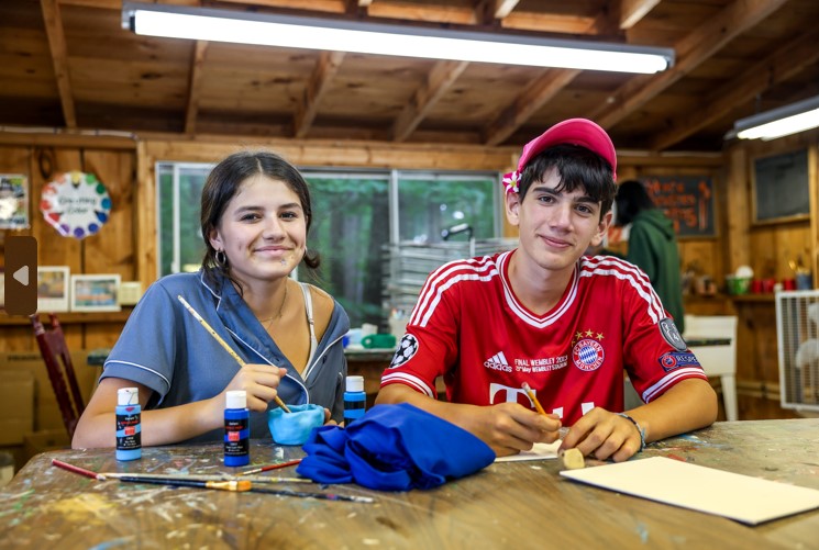 Teens enjoying arts and crafts at a summer camp, painting and creating together in a rustic cabin setting. Teens enjoying arts and crafts at a summer camp, painting and creating together in a rustic cabin setting.