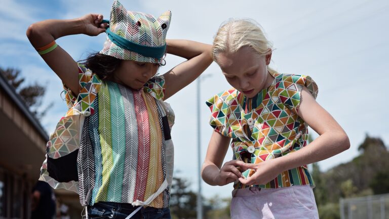 Two kids in colorful outfits enjoying a sunny day at a summer camp, perfect for creative adventures and fun.