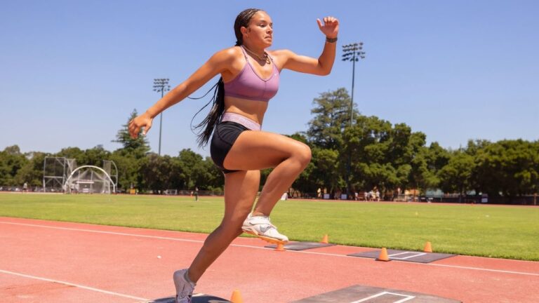 Athlete jumping on track at summer sports camp, showcasing dynamic exercise and outdoor activity skills.