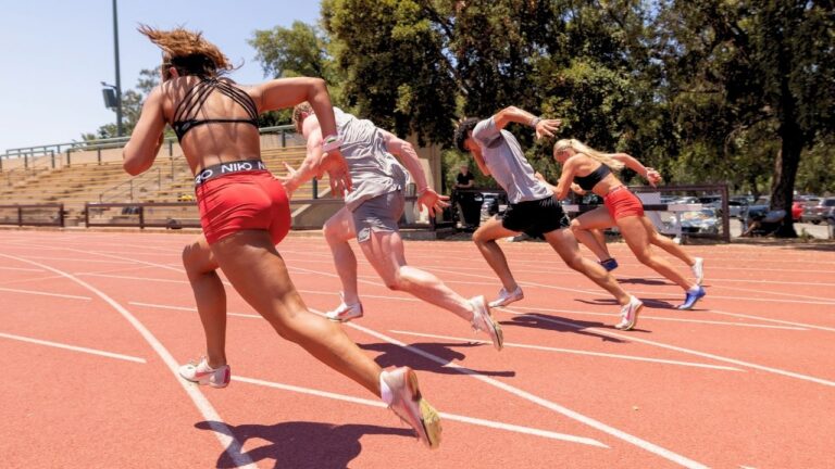Youth athletes sprinting on a sunny track at summer camp, enhancing skills and fitness.