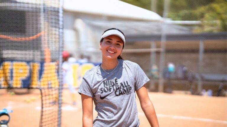 Teen girl smiling at Nike Softball Camp, sunny day, summer camp fun and athletics.