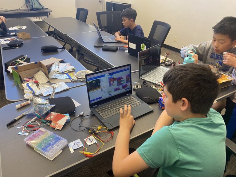 Children engaged in coding and electronics projects at a summer camp technology workshop. Children engaged in coding and electronics projects at a summer camp technology workshop.