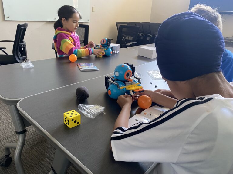 Children learning robotics at a summer camp, engaging with educational toys in a classroom setting. Children learning robotics at a summer camp, engaging with educational toys in a classroom setting.
