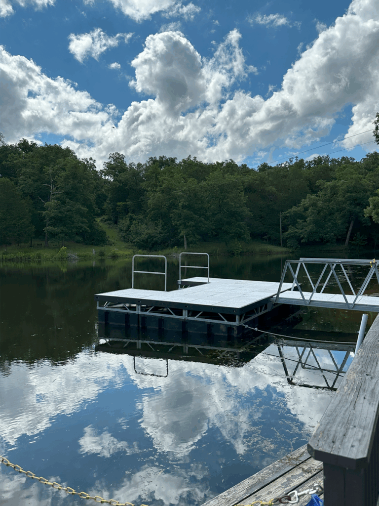 Floating dock on a clear lake surrounded by trees, perfect for summer camp activities and outdoor fun. Floating dock on a clear lake surrounded by trees, perfect for summer camp activities and outdoor fun.