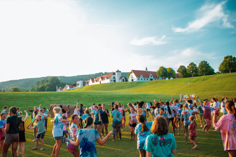 Kids having fun at a summer camp color festival on a sunny day, with a scenic building and trees in the background. Kids having fun at a summer camp color festival on a sunny day, with a scenic building and trees in the background.