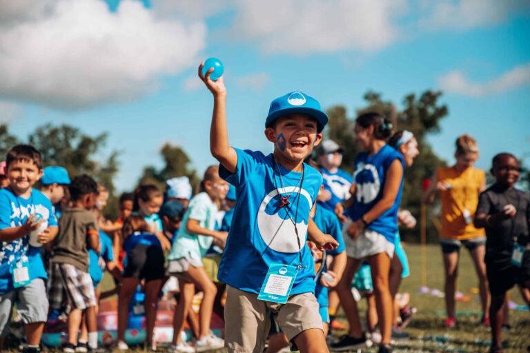 Happy kids play at summer camp activity outdoors, enjoying games in the sun.