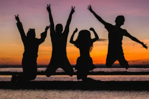 Kids jumping in joy at summer camp sunset, creating lifelong memories. Perfect camp directory highlight.