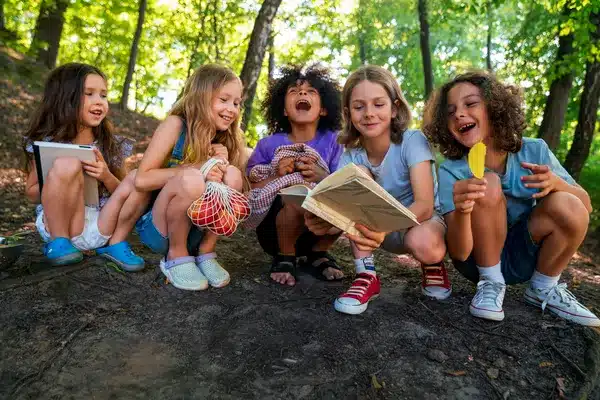 Children enjoying a book and nature at a fun summer camp in the woods. Perfect spot for reading and adventure.