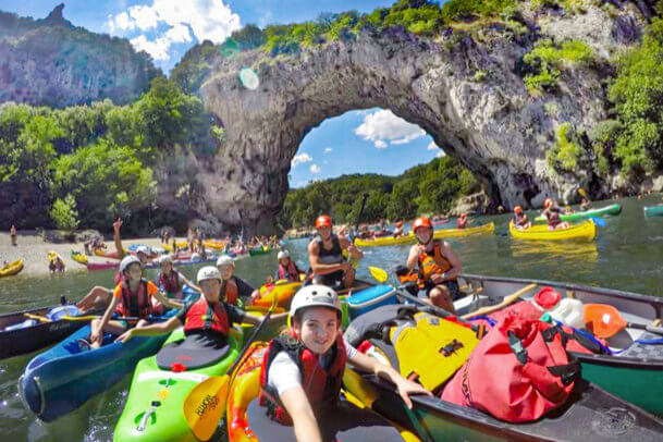 Campers kayaking under natural rock arch, enjoying summer adventures at camp. Perfect outdoor activity for kids and teens. Campers kayaking under natural rock arch, enjoying summer adventures at camp. Perfect outdoor activity for kids and teens.