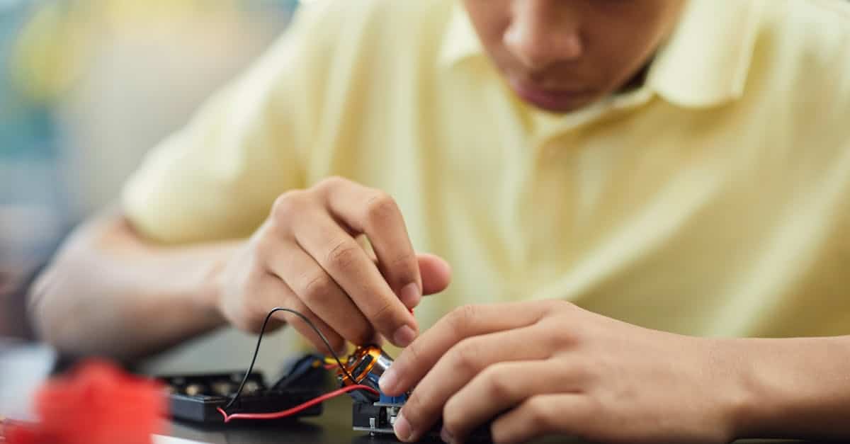 Child building electronics at summer camp, fostering STEM learning and creativity.