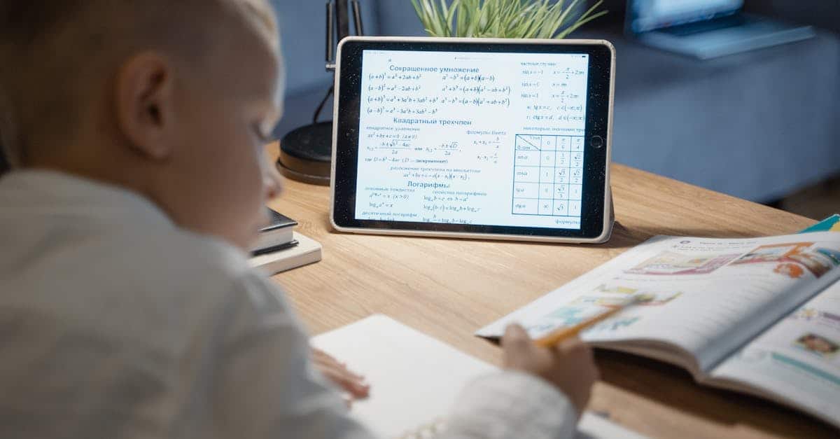 Child learning math at summer camp using a tablet and workbook. Fun educational activities for kids.