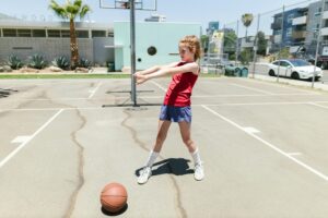 Kid playing basketball at summer camp, outdoor fun on court. Discover camps near you for active kids!