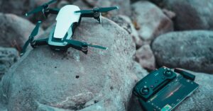 Drone and controller on rocks at summer camp for outdoor tech enthusiasts.