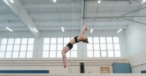 Gymnast performing on balance beam at summer camp indoors.