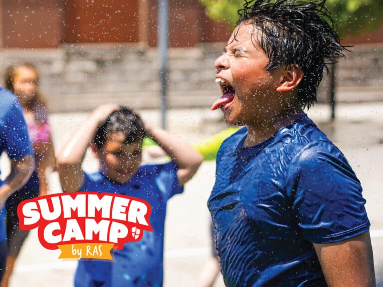 Children at summer camp enjoying outdoor water games — boy in blue shirt laughing as water splashes Children at summer camp enjoying outdoor water games — boy in blue shirt laughing as water splashes