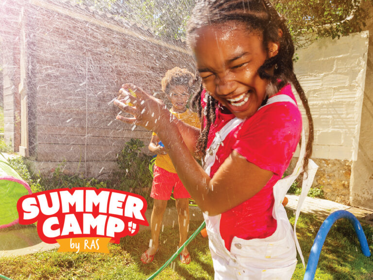 Kids at summer camp laughing and splashing under a garden hose sprinkler during outdoor water play Kids at summer camp laughing and splashing under a garden hose sprinkler during outdoor water play
