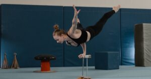 Gymnast performing a handstand on parallel bars in a training facility, showcasing skill and strength.