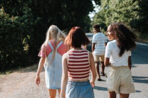 Group of friends walking together on a sunny day, enjoying their summer camp adventure. Fun and friendship in nature!